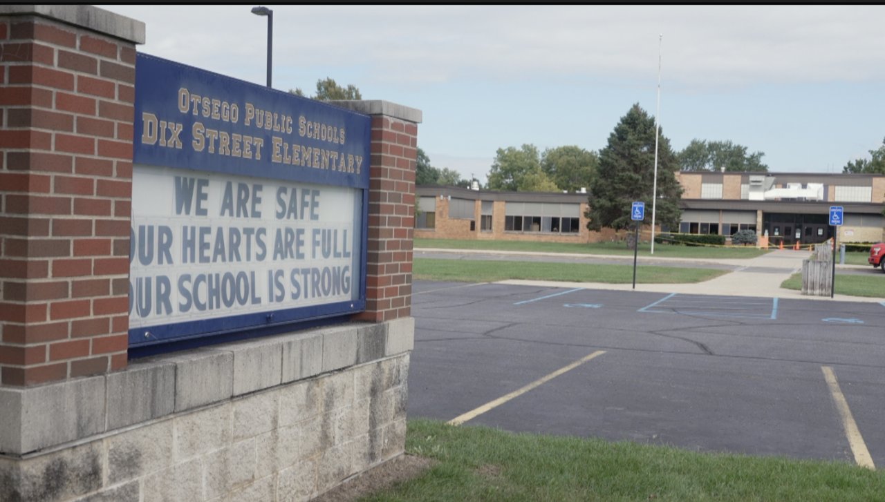 Placa da Dix Street Elementary, das escolas públicas de Otsego, em frente ao estacionamento e ao prédio da escola